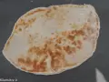 Un naan au fromage, peut-être avec un peu de La Vache qui rit, doré et moelleux, prêt à être dégusté.