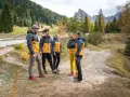 Gruppo di escursionisti con giacche imbottite gialle e blu, pantaloni tecnici e scarponi. Perfetto esempio di come vestirsi in montagna per un'avventura autunnale.