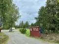 Välkommen till ställplatsen vid Skeda strand. En husbil står parkerad bland träden.