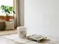 Un cubo de pintura anticondensación y un rodillo esperan para renovar la pared. ¡Se puede pintar encima de pintura anticondensación sin problema!