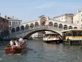 Gondola e vaporetti navigano sul Canal Grande sotto il maestoso Ponte di Rialto, un'icona di Venezia.