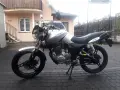 Srebrny Zipp Manic 125 na brukowanym podwórku, gotowy do jazdy.