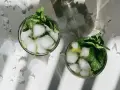 Dwa orzeźwiające mojito z lodem i miętą, otoczone pokruszonym lodem, w letnim słońcu.