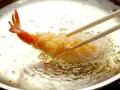 Krewetka w chrupiącej panierce panko smaży się na złoto w gorącym oleju.