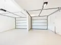 Dos puertas de garaje se abren a un espacio limpio y moderno, listo para pintar el garaje original.