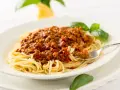 Ein Teller Spaghetti mit einer reichhaltigen, traditionell zubereiteten Bolognese-Sauce, garniert mit frischem Basilikum.