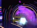 Żółty Fiat Panda wyjeżdża z dymu i świateł w kole fortuny.