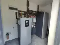 Nowoczesna instalacja grzewcza z pompą ciepła wysokotemperaturową, zbiornikiem i systemem rur.