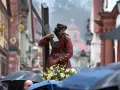 Prozession am Karfreitag: Jesus trägt das Kreuz. Gläubige mit Regenschirmen gedenken.