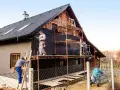 Pracownicy na rusztowaniach ocieplają dom. Określenie ceny ocieplenia za 1m2 robocizna jest kluczowe dla tego projektu.