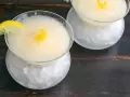 Dos copas de sorbete de limón, una con rodaja de limón y rizo de cáscara, servidas sobre hielo picado.