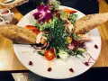 Kolorowy, świeży sałatka z rybą, pieczywem i kwiatem orchidei. Idealna propozycja, co zjesc w Jeleniej Górze.