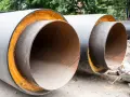 Izolowane rury wodne, gotowe do montażu. Pokazują, jak ocieplić rury z wodą na zewnątrz, chroniąc je przed mrozem.