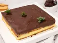 Deliciosa tarta de la abuela con capas de galleta y crema, cubierta de chocolate y decorada con menta fresca.