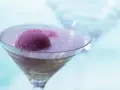 Ein erfrischendes Eis mit Sekt in einem Martiniglas. Die pinke Eiskugel schwimmt in prickelndem Sekt, ein Genuss für heiße Tage.