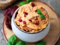 Cremige Tomatenbutter, garniert mit Basilikum und getrockneten Tomatenstücken. Perfekt für ein einfaches Tomatenbutter Rezept.