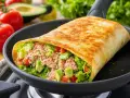 Un wrap garni de thon, avocat et tomates, prêt à être dégusté. Une recette wrap facile et rapide pour un repas sain.