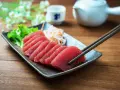 Pyszne japońskie ryby, świeże sashimi z tuńczyka, podane z sałatką i sosami. Pałeczki gotowe do degustacji.