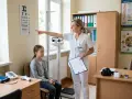 Pielęgniarka podczas indywidualnej praktyki pielęgniarskiej bada wzrok dziewczynki, wskazując na tablicę Snellena.