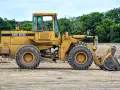 Żółta koparko-ładowarka John Deere 624G gotowa do pracy, wymaga odpowiednich uprawnień do obsługi.