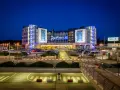 Nowoczesny hotel Radisson Blu Hamburg Airport nocą, z podświetlanym logo i parkingiem pełnym samochodów.