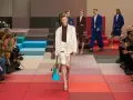 Modella sfila in passerella, un'icona di stile che scrive la sua **fendissime storia**. Pubblico con smartphone documenta l'evento.