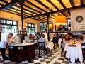 Un camarero prepara platos en un restaurante lleno de comensales. Los pasos para abrir un restaurante incluyen crear un ambiente acogedor como este.