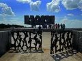 Brama pamięci na terenie byłego obozu Majdanek. Grupa ludzi zwiedza miejsce pamięci.