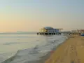 Alba dorata sul mare di Senigallia, con il celebre edificio sul mare e la spiaggia che si estende verso la città.