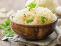 Schüssel mit Sauerkraut, garniert mit Petersilie und Pfefferkörnern. Dieses fermentierte Gericht ist bekannt dafür, dass Sauerkraut gesund ist.