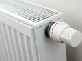 Biały grzejnik z termostatem. Różne rodzaje grzejników oferują różne sposoby regulacji temperatury.