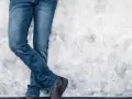 Mężczyzna w jeansach H&M, stojący przy ścianie. Rozmiarówka H&M wypada standardowo, idealnie dopasowana.