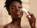 Donna con pelle scura usa un dispositivo per un trattamento esfoliante viso, per una pelle luminosa e pulita.