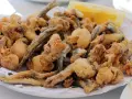 Frito y crujiente pescado en adobo, con trocitos de calamar y una rodaja de limón.