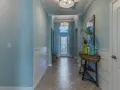 Un couloir lumineux avec une peinture de couloir 2 couleurs : bleu ciel et blanc. Un banc, une console avec des vases et une porte vitrée ornent cet espace accueillant.