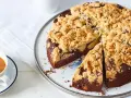 Ein saftiger Apfel Schokoladenkuchen mit knuspriger Streuseldecke, daneben eine Tasse Kaffee.