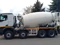 Biała betonomieszarka z obracanym bębnem, zaparkowana na zewnątrz.