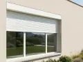 Instalación de persianas enrollables blancas en una casa moderna. El jardín y las colinas se reflejan en los cristales.