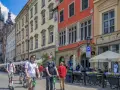 Młodzi ludzie na hulajnogach w Krakowie, idealne na city break. W tle Sukiennice i Kościół Mariacki.