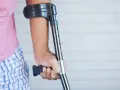 Osoba z kulą, być może po wypadku, który mógłby być opisany jako art. 156 kk. Różowa koszulka i kratkowane spodenki.