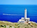Faro di Punta Palascìa, uno dei luoghi da vedere a Otranto, con il mare blu e una barca in lontananza.