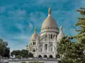 Basílica del Sacré-Cœur, uno de los monumentos de Francia, se alza majestuosa bajo un cielo azul con nubes.