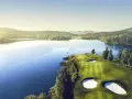 Vacker golfbana vid en sjö, perfekt för norsk golf. Grönskande kullar och solnedgång.