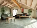 Nowoczesny salon z drewnianymi belkami i gładką, szarą posadzką z żywicy.