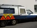 Dwukolorowy Citroen C15 z nietypowymi oznaczeniami "UX" i "Xi Xn" na boku, zaparkowany przy białej ścianie.