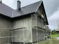 Dom w trakcie ocieplania, rusztowania wokół ścian. Zastanawiasz się, ile kosztuje ocieplenie domu?