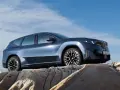 Niebieskie BMW iX3 na tle błękitnego nieba, stojące na skalistym podłożu.