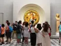 Galeria Uffizi: co zobaczyć? Grupa turystów podziwia okrągły obraz w złotej ramie i rzeźbę.