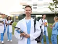 Uśmiechnięty student medycyny z książkami, gotowy na wyzwania studiów psychologicznych. Wymagania są wysokie, ale cel jest jasny.