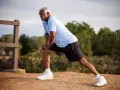 Un homme âgé s'étire pour muscler ses cuisses, un exercice simple en extérieur.
